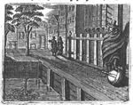 Man with his foot on an orb on a canal street; man and woman talking in the distance.