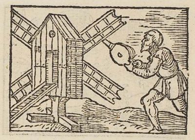 A man blowing at a windmill with a bellows